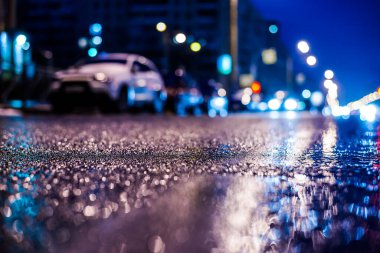 Büyük şehirde yağmurlu bir gece, su birikintileri olan boş bir yol.