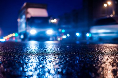Büyük şehirde yağmurlu bir gece, parlak vitrinleri olan bir cadde. 