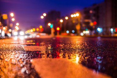 Park yerindeki alışveriş merkezinde yağmurlu bir gece, sıra sıra park edilmiş arabalar..