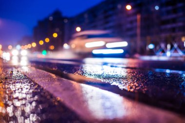 Park yerindeki alışveriş merkezinde yağmurlu bir gece, sıra sıra park edilmiş arabalar..