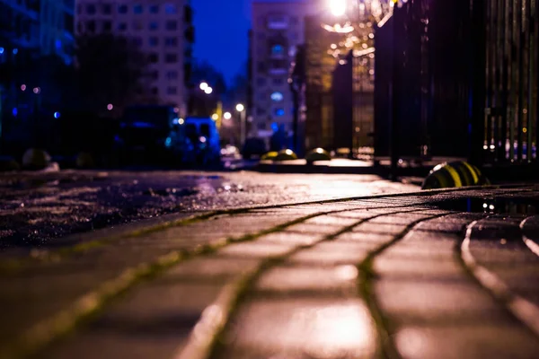 Night in the city yard, empty road with lantern light.