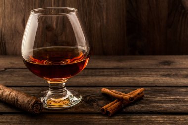 Bir bardak brendi ve ahşap bir masada tarçın çubuğu.. 