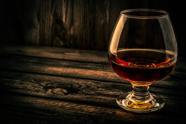 Glass of brandy and on an old wooden table.