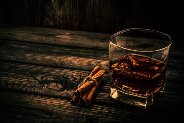 Bir bardak brendi ve jüt halatla bağlanmış tarçın çubukları.