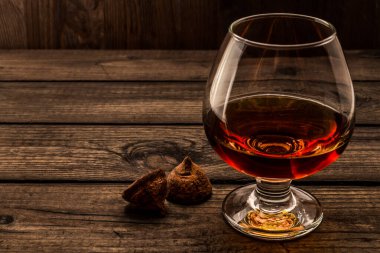 Glass of brandy and a couple of chocolate truffles on an old wooden table