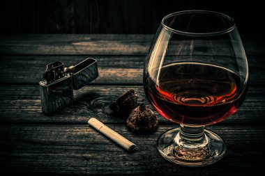 Eski ahşap bir masada bir bardak brendi ve çikolatalı trüf.. 