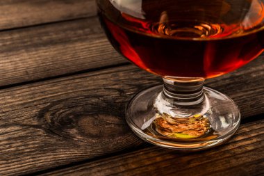 Glass of brandy on an old wooden table. 