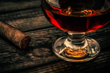 Bardak brendi ve puro eski ahşap masa.