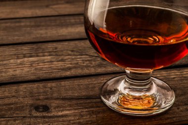 Glass of brandy on an old wooden table. 