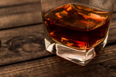 Glass of brandy and on an old wooden table. Close up view