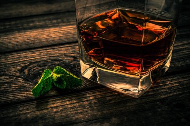 Nane filizi ve ahşap kalaslı bir bardak brendi.