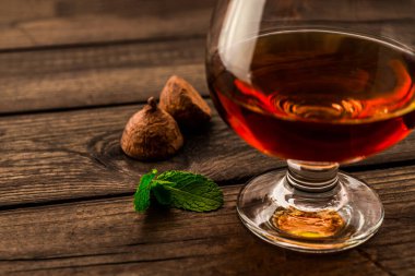 Eski ahşap bir masada bir bardak brendi ve çikolatalı trüf.. 