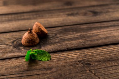 Chocolate truffles with mint sprig on an old wooden table. 