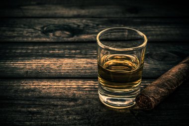 Eski ahşap bir masada Küba purosuyla bir bardak tekila.