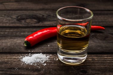 Eski ahşap bir masada kırmızı biberli bir bardak tekila..