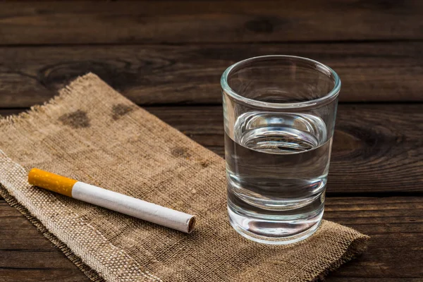 Shot of vodka with piece of cloth and cigarette on an old wooden