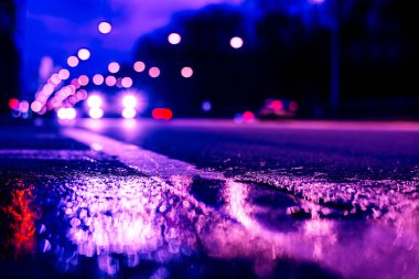 Gece şehir ışıkları gece yolundaki su birikintisine yansıyor..