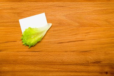 Tahta masadaki notlar için marul ve boş kart. 