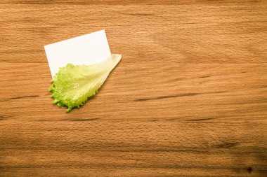 Tahta masadaki notlar için marul ve boş kart.