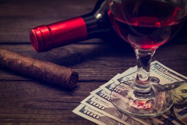 Bottle of red wine with a glass of red wine and cuban cigar on an old wooden table 