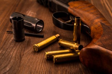 Boş kabuklu ve boğma tüplü tüfekler ahşap bir masada yatıyor..