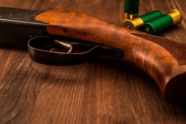 Tahta bir masada duran mermili av tüfeği. Görüntüyü kapat