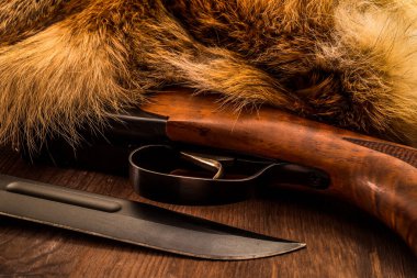 Avcı tüfeği ve savaş bıçağı hayvanın kürkünün yanında duruyordu. 