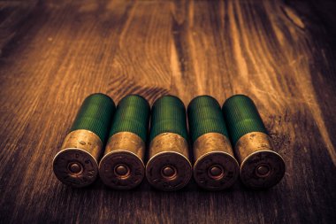 Tahta bir masanın üzerinde duran 12 kalibrelik kartuş.