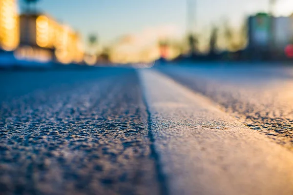 Sunny day in a city, asphalt lit by the rays of the setting sun.