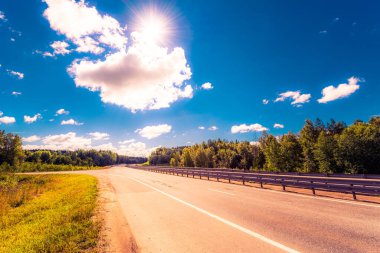 Kırsal yol tarlalardan ve ağaçlardan geçiyor.