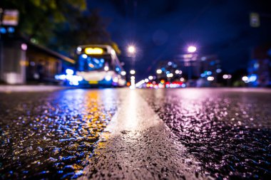 Gece gündüz yağmur yağıyor, yaklaşan otobüsün parlayan ışıkları. Vi