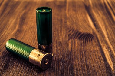 Tahta bir masanın üzerinde iki tane 12 kalibrelik kurşun var.