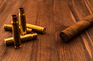 Tüfeğin boş kovanları ve Küba purosu tahtanın üzerinde yatıyordu.