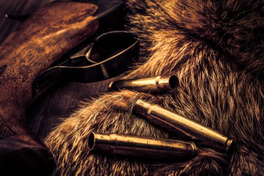 Hayvanların kürkünün yanında duran av tüfeği.