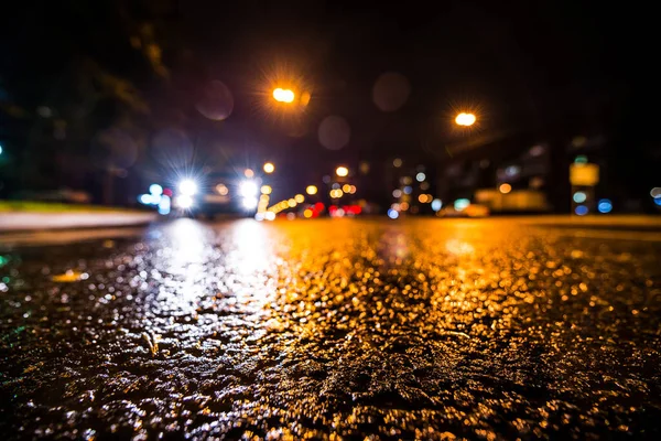 Night city after rain, approaching car headlights shine. View fr