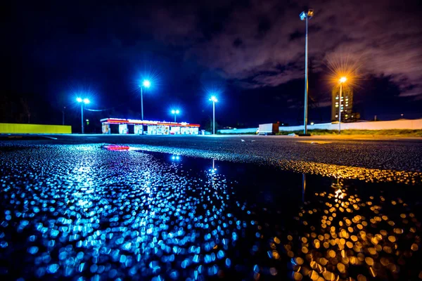 Night city after rain, lights illuminating the parking lot near