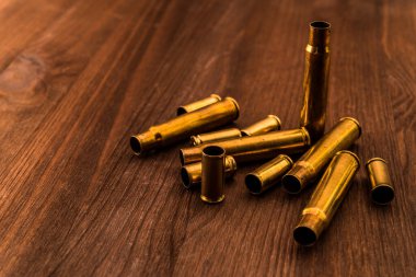 Tahta bir masada duran silahlardan çıkan boş mermiler.