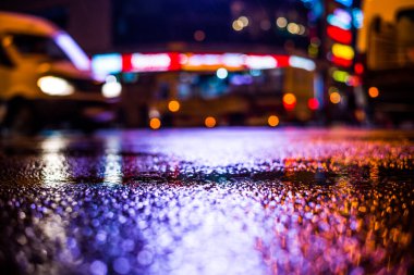 Büyük şehirde yağmurlu bir gece, parlayan vitrinler ve araba