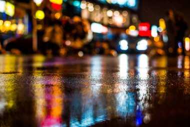 Büyük şehirde yağmurlu bir gece, vitrinlerden yansıyan ışıklar