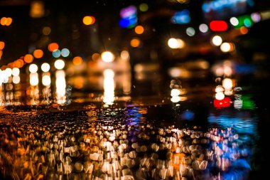 Büyük şehirde yağmurlu bir gece, vitrinlerden yansıyan ışıklar