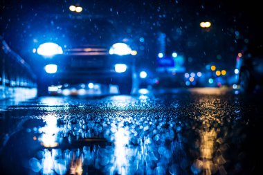 Büyük şehirde yağmurlu bir gece, Trave arabasının farları yaklaşıyor.