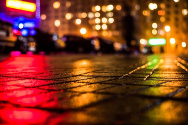 Büyük şehirde yağmurlu bir gece, dükkan pencerelerinden gelen ışık ve...