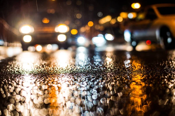 Büyük şehirde yağmurlu bir gece, Trave arabasının farları yaklaşıyor.