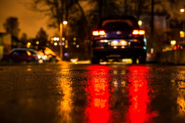 Rainy night in the big city, city alley with trees and a parked