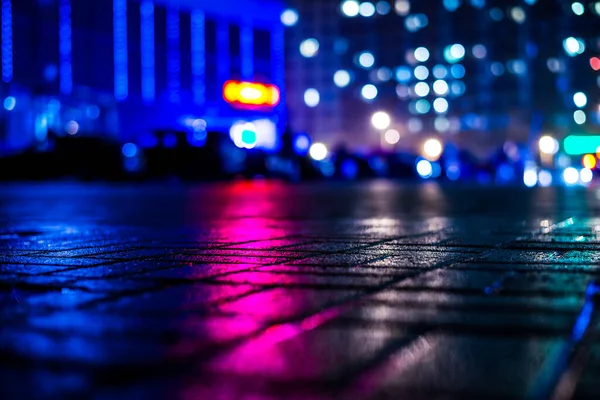 Büyük şehirde yağmurlu bir gece, dükkan pencerelerinden gelen ışık ve...