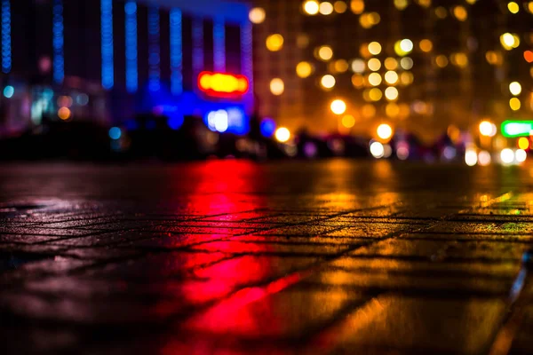 Büyük şehirde yağmurlu bir gece, dükkan pencerelerinden gelen ışık ve...