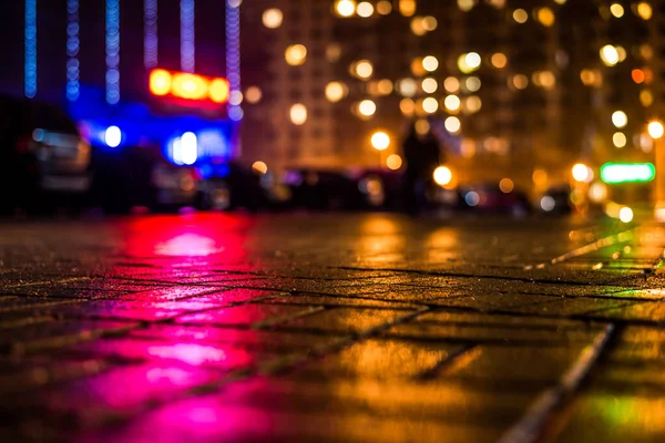 Büyük şehirde yağmurlu bir gece, dükkan pencerelerinden gelen ışık ve...