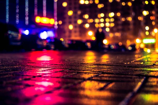 Büyük şehirde yağmurlu bir gece, dükkan pencerelerinden gelen ışık ve...