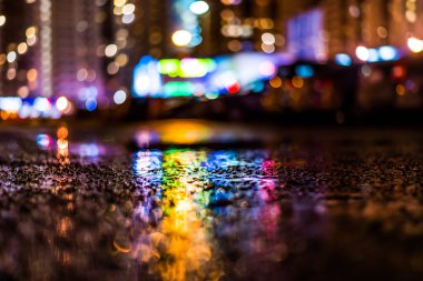 Gece manzarası, ıslak asfalta yansıyan renkli ışıklar.