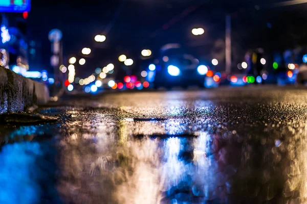 Night city after rain, view of the flow of cars from the curb at